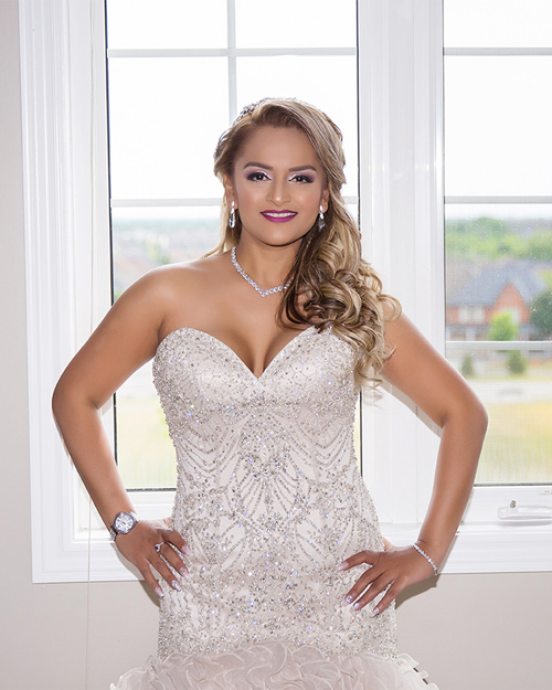 Smiling bride in white gown with CN Tower in the background, downtown Toronto.