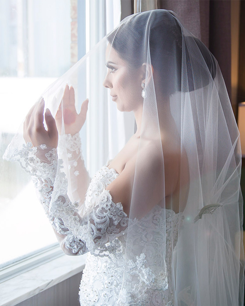 Smiling bride in white gown with CN Tower in the background, downtown Toronto.