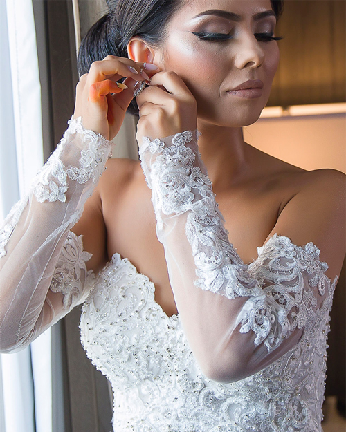 Smiling bride in white gown with CN Tower in the background, downtown Toronto.