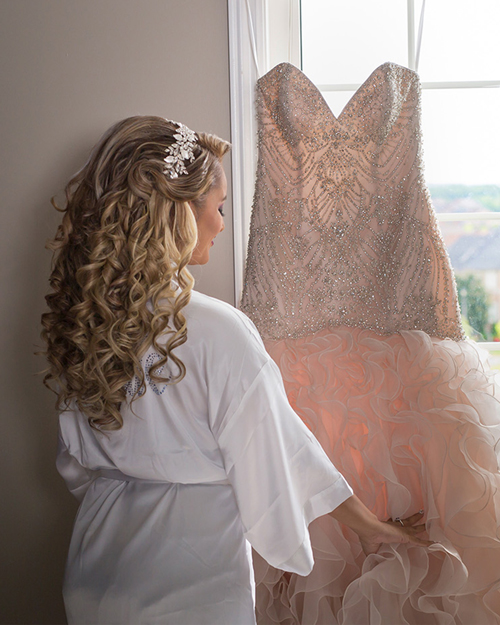 Smiling bride in white gown with CN Tower in the background, downtown Toronto.
