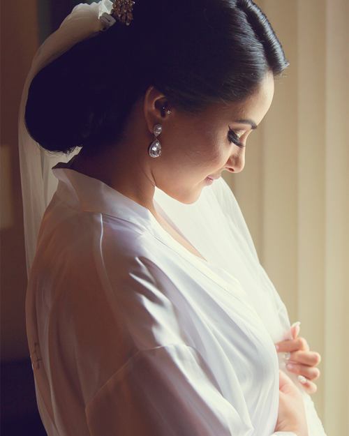 Smiling bride in white gown with CN Tower in the background, downtown Toronto.
